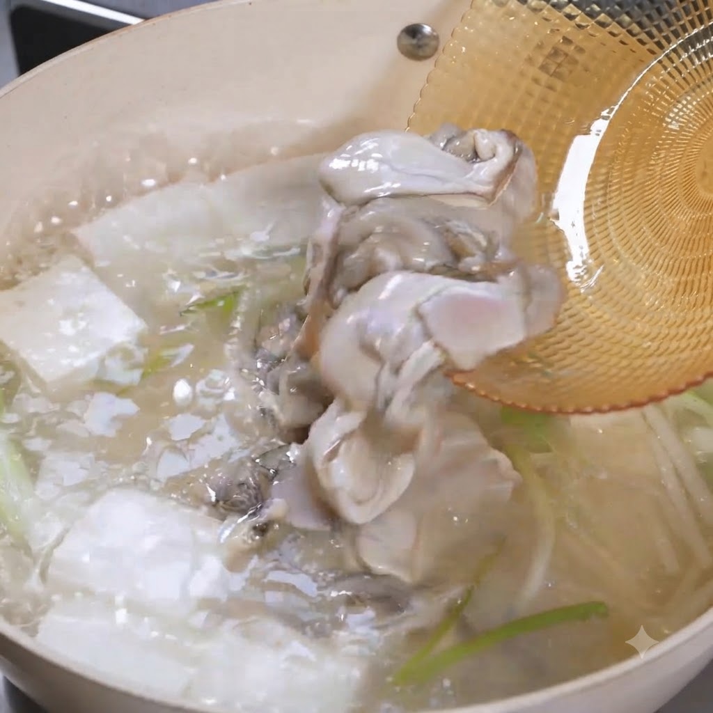 Carne de ostra cruda deslizándose desde una espumadera hacia una olla burbujeante de sopa de tofu.