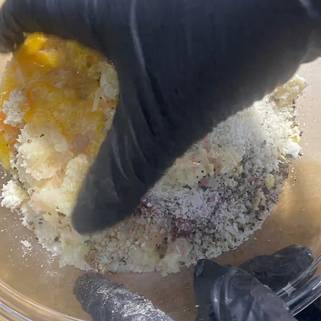 Manos con guantes mezclando y amasando a fondo el relleno de carne dentro del bol de vidrio.