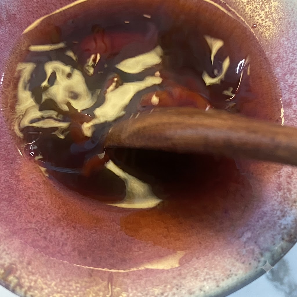 La mezcla de salsa teriyaki siendo revuelta con una cuchara de madera en el bol.