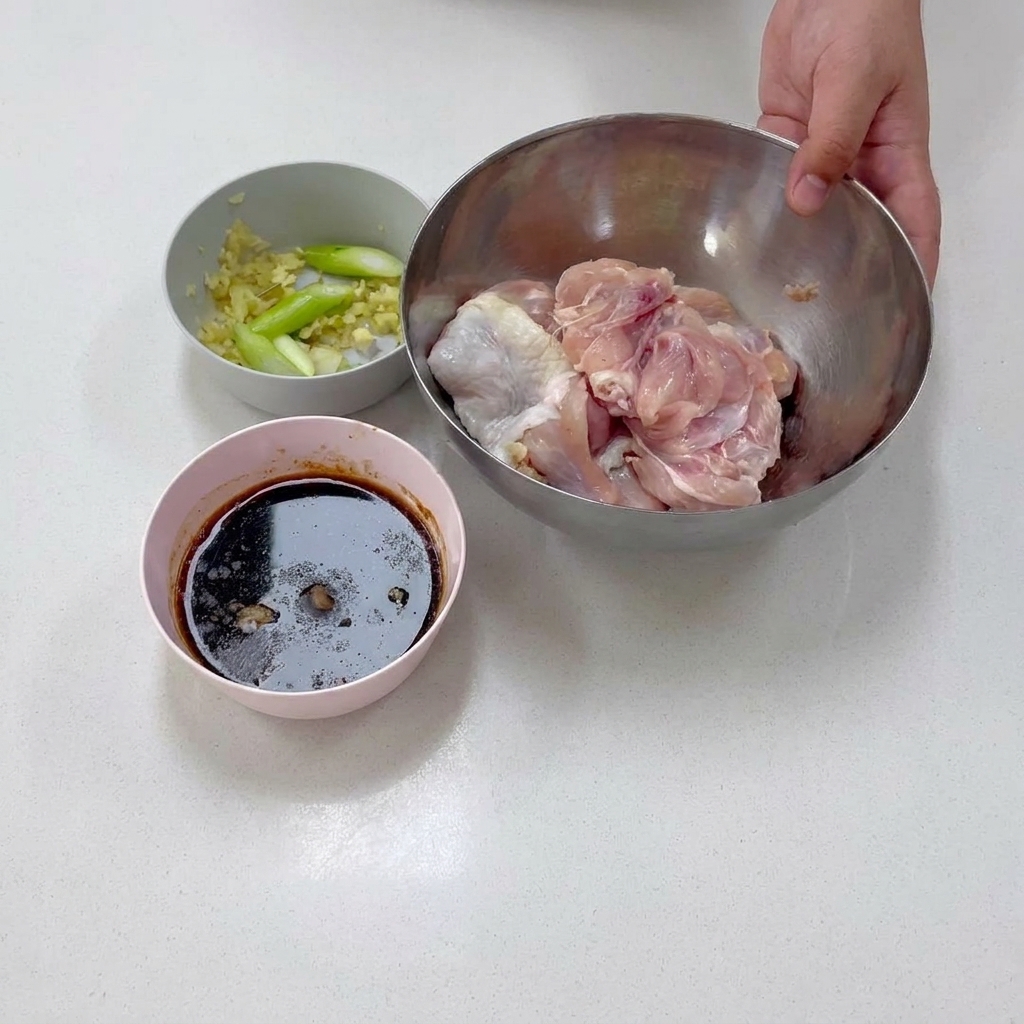 Carne de pierna de pollo sin hueso reposando dentro de un tazón de acero inoxidable durante la preparación.