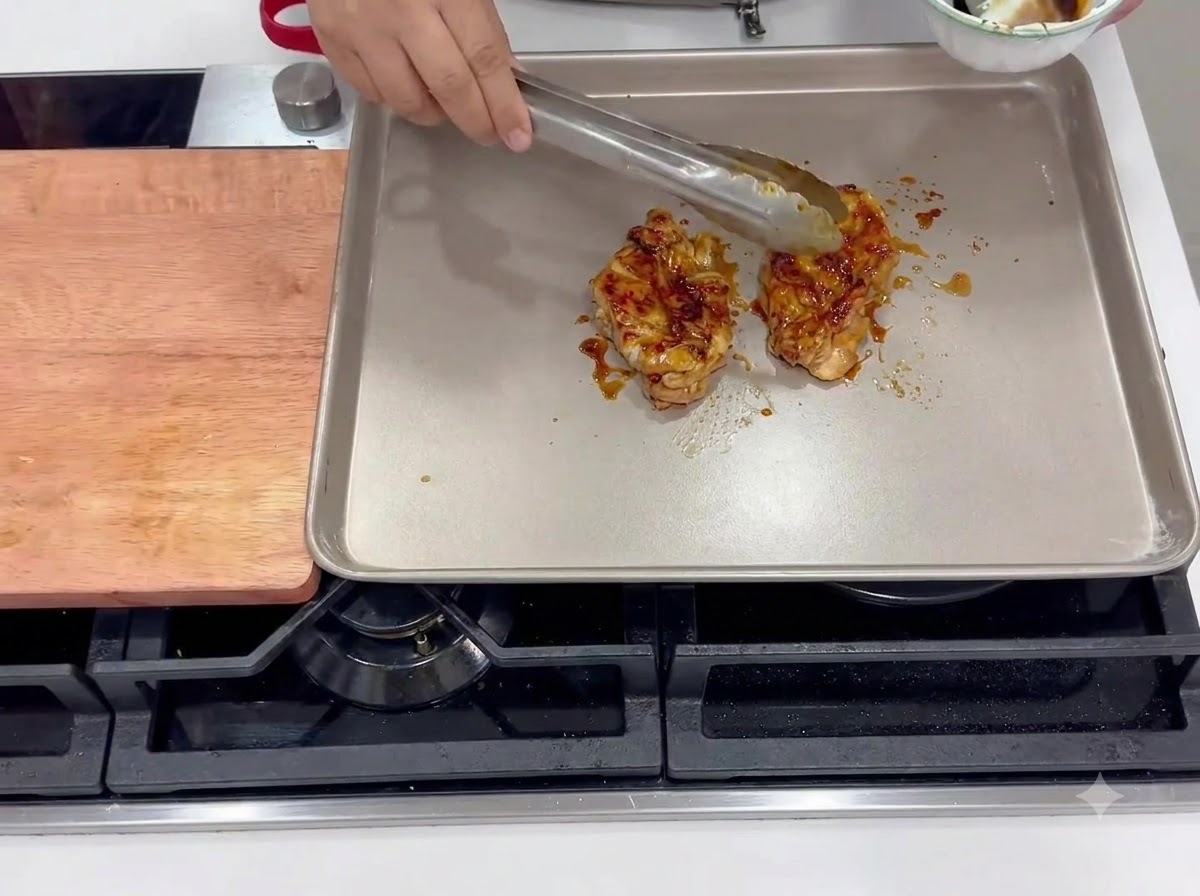Muslos de pollo marinados friéndose con la piel hacia abajo en una sartén cuadrada caliente.
