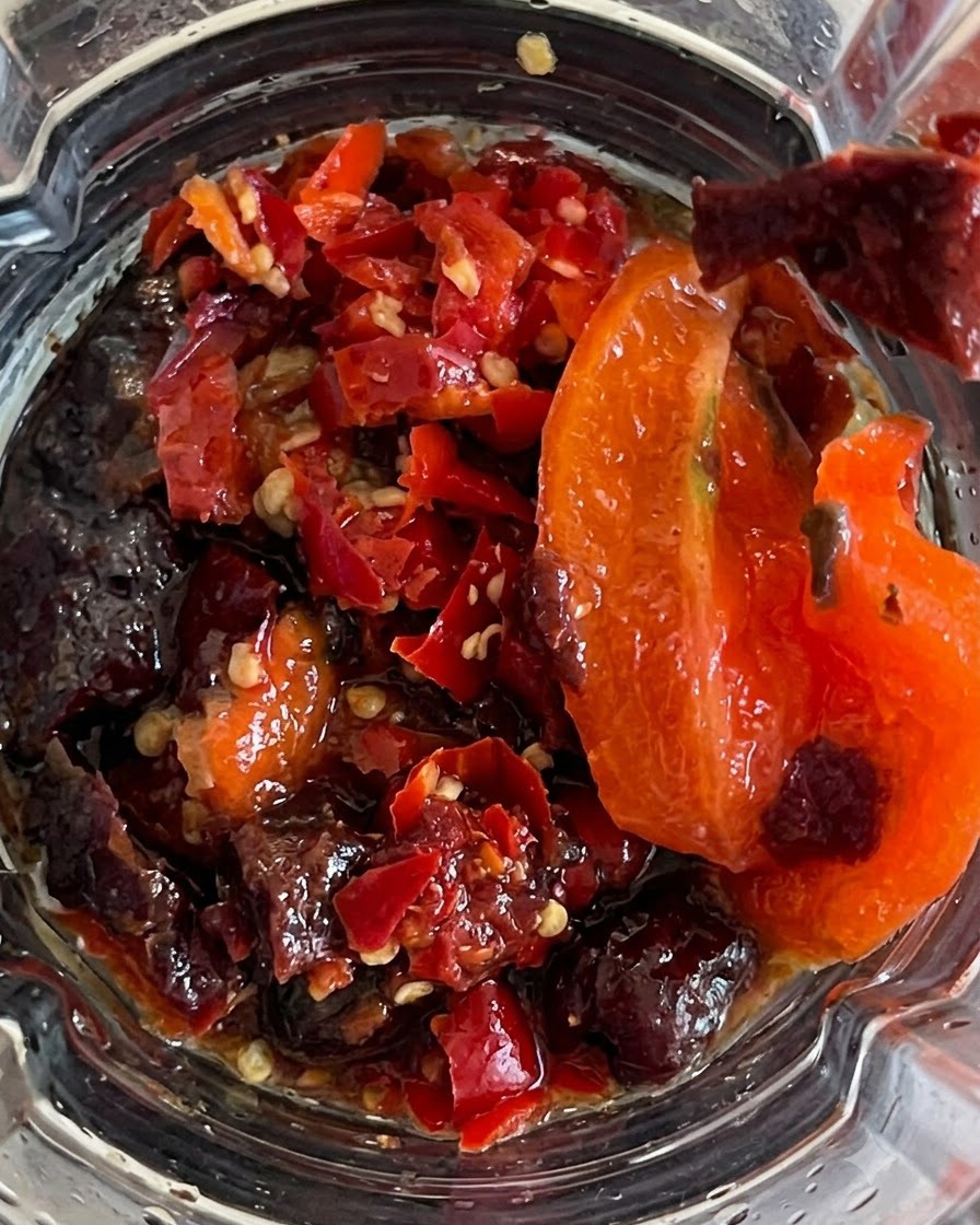 Todos los ingredientes siendo licuados dentro del recipiente formando una salsa picante espesa.