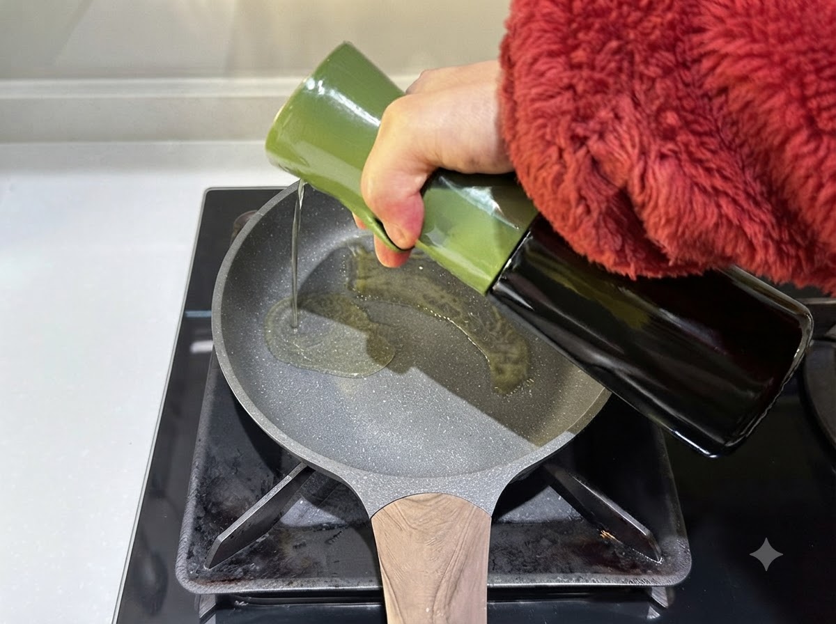 Aceite de oliva siendo vertido desde un envase verde en una sartén caliente.