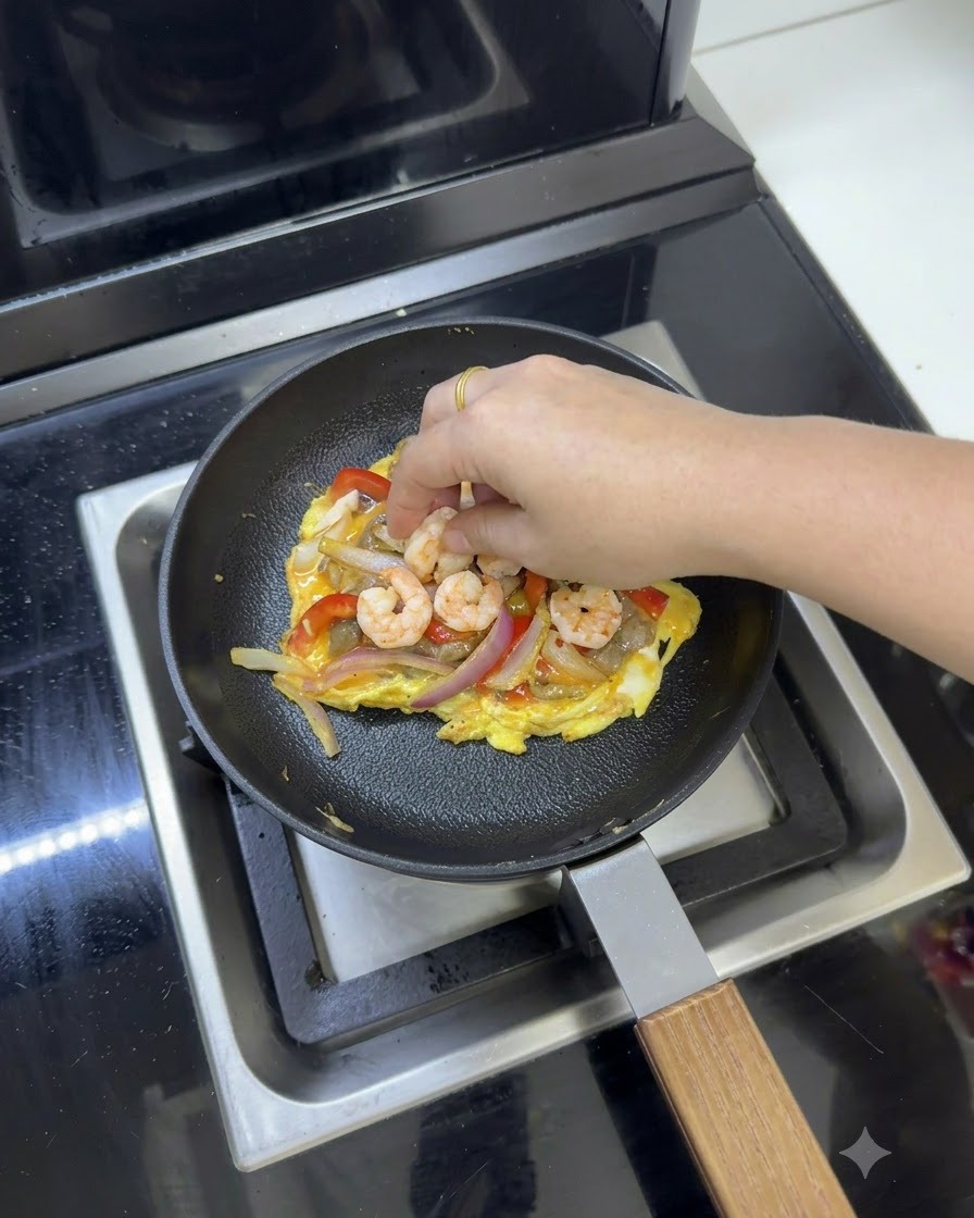 Rebanadas de queso fundente colocadas sobre la mezcla de huevo y verduras en la sartén.