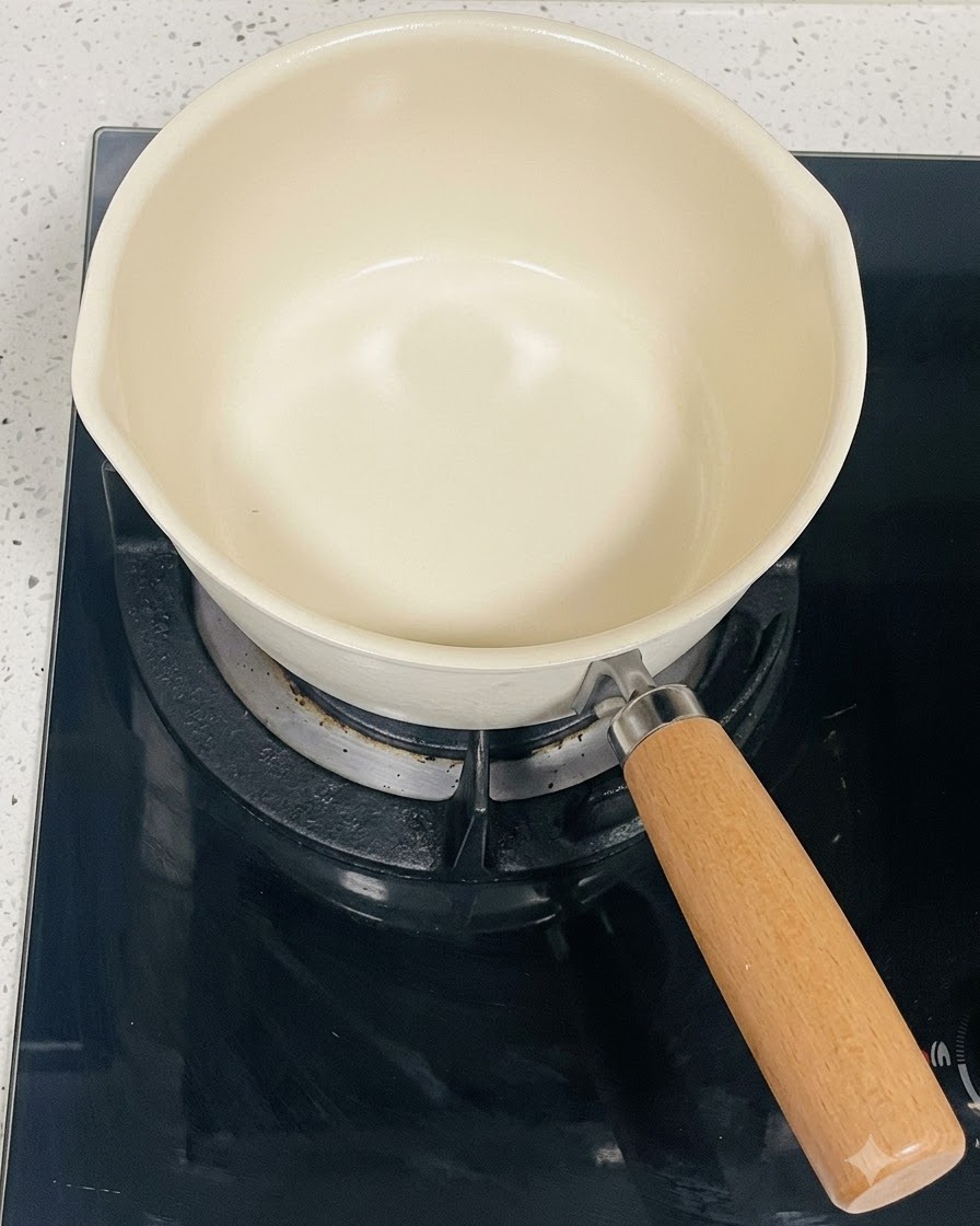 Una olla de cocina limpia de color crema sobre un quemador de cocina de inducción negro.