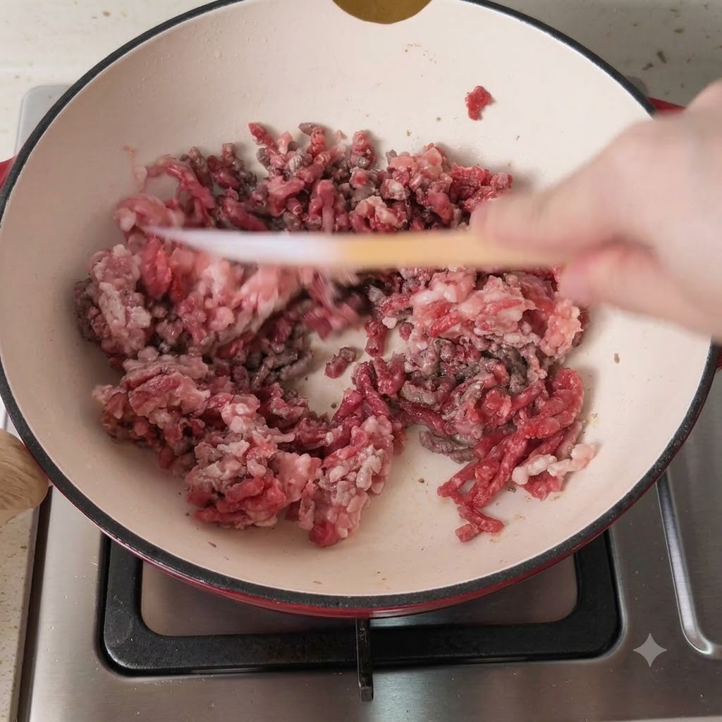 Carne picada mixta de cerdo y ternera dorándose en una olla caliente.