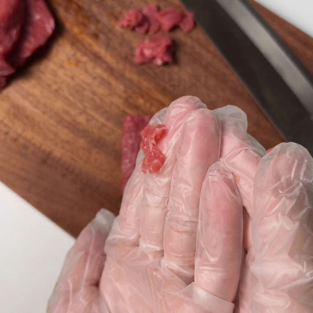 Lomo de ternera en rodajas mezclándose a mano con condimentos en un bol.