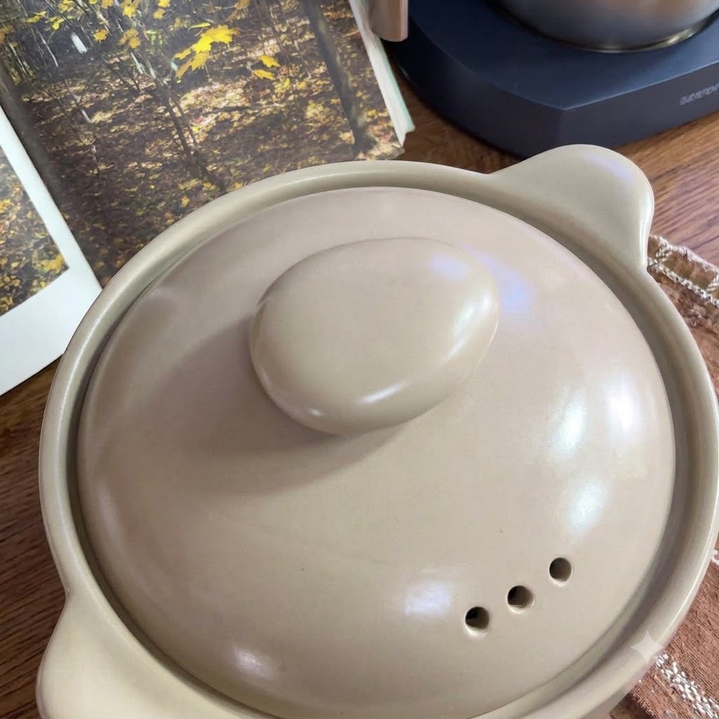 Tomates frescos dispuestos en una bandeja junto a una olla de cerámica.