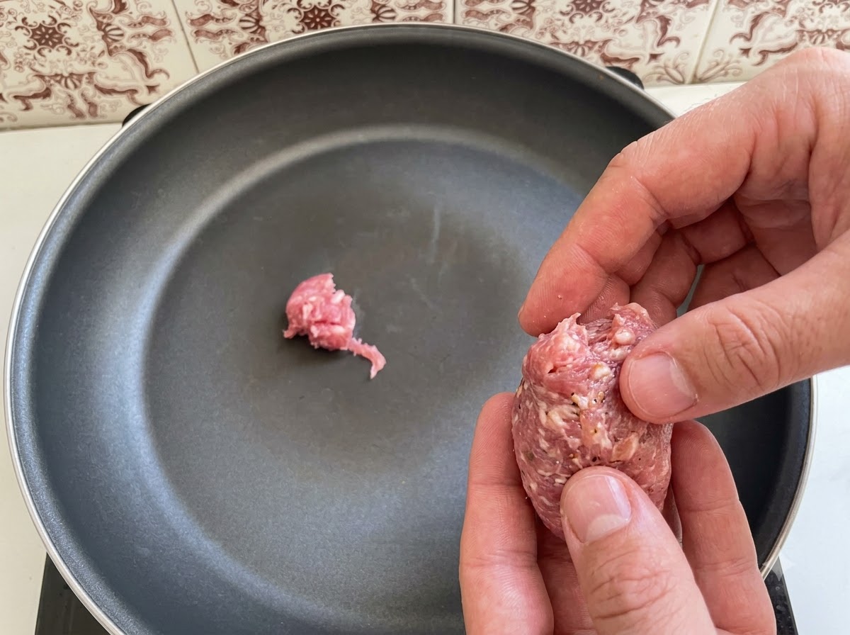 Trozo de carne de salchicha italiana siendo organizados y colocados en una sartén.