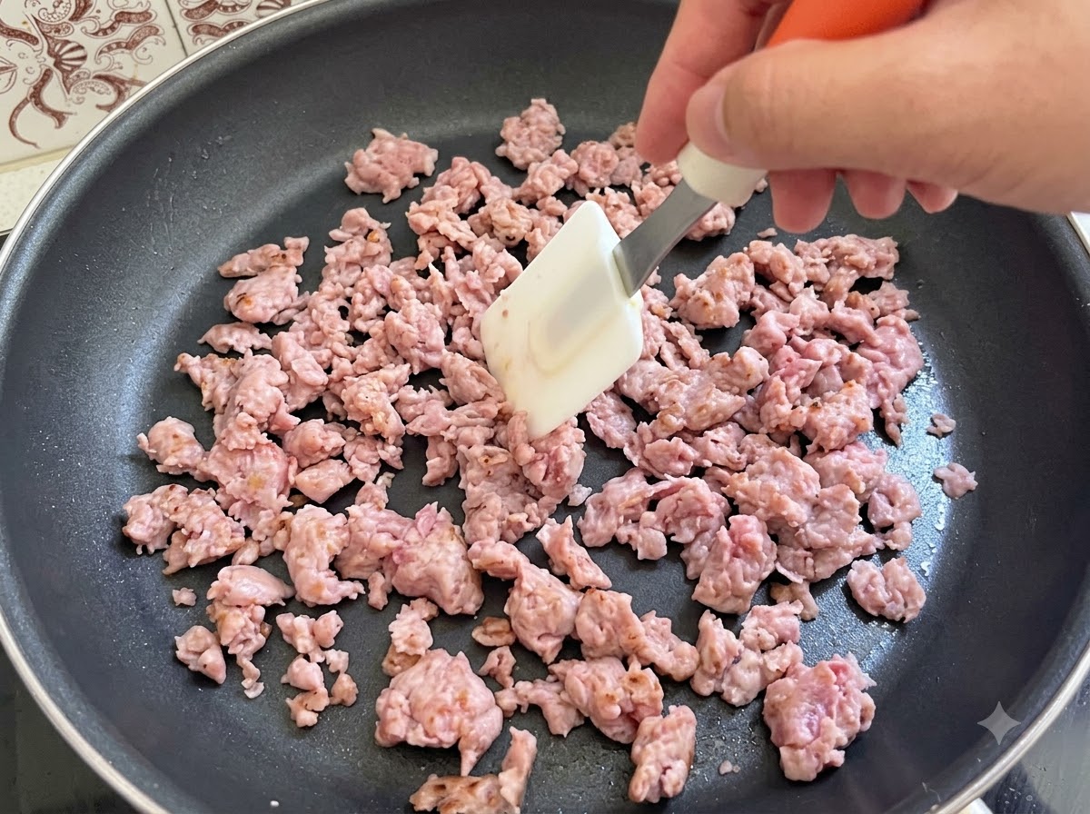 Carne de salchicha italiana siendo revuelta y frita activamente con una espátula en una sartén.