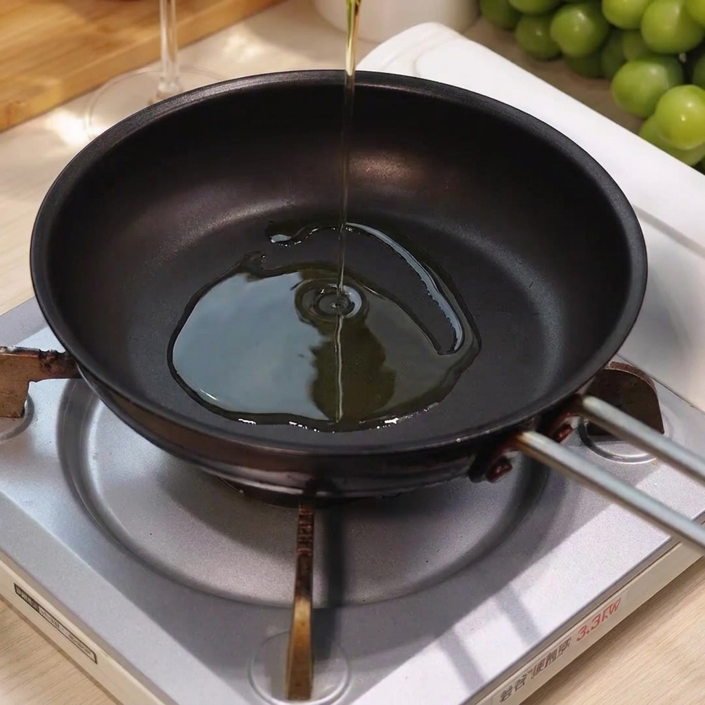 Aceite de oliva siendo vertido en el centro de una sartén caliente y vacía sobre un quemador.