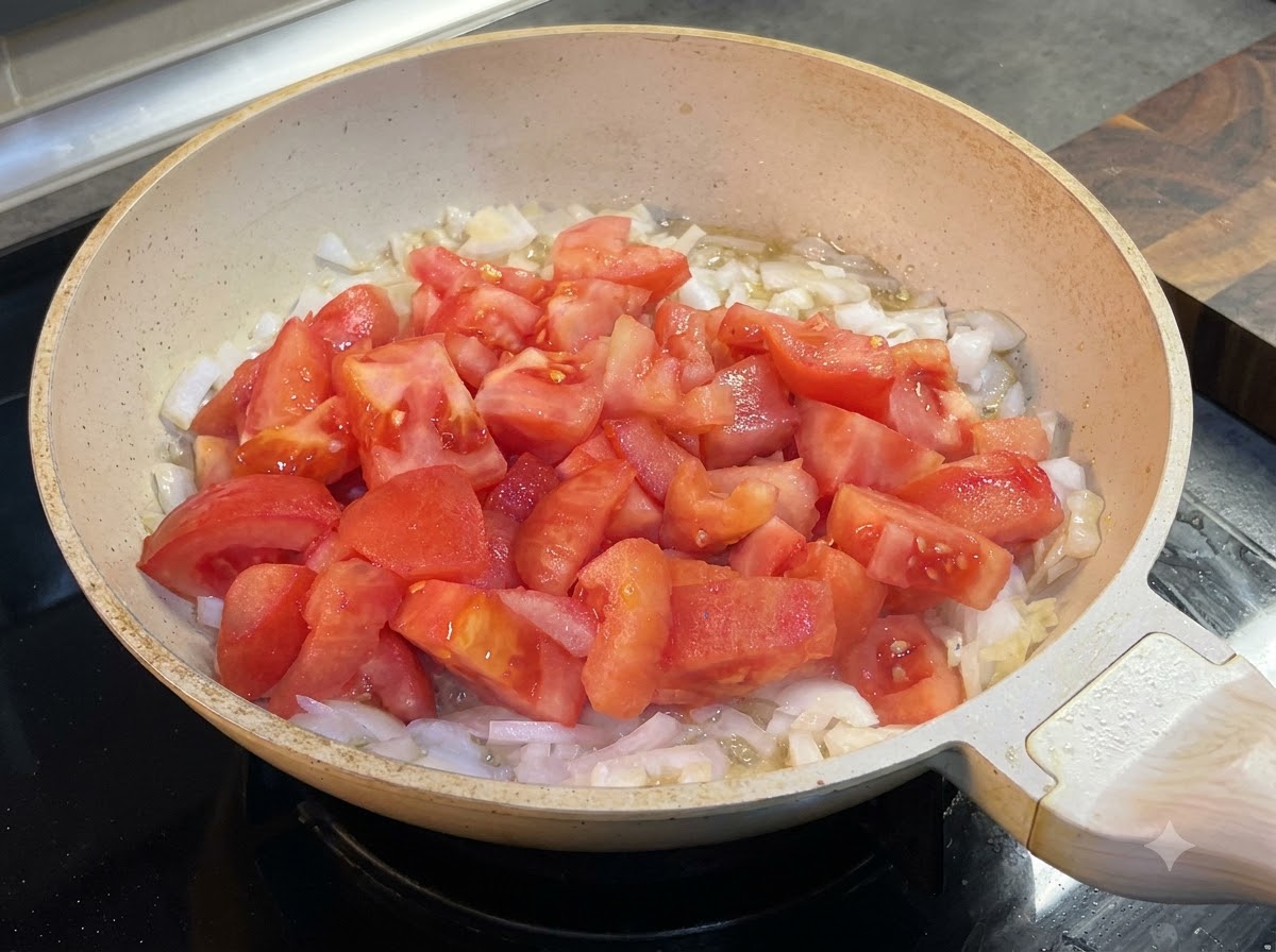 Kétchup siendo añadido a la sartén con tomates y cebollas.
