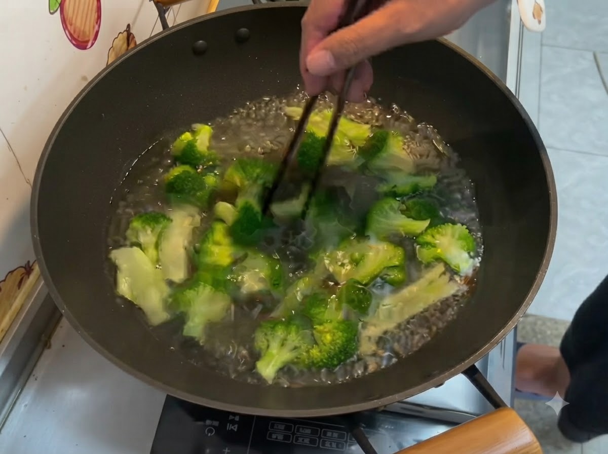 Floretes de brócoli verde brillante hirviendo en agua dentro de un wok, removidos con palillos.