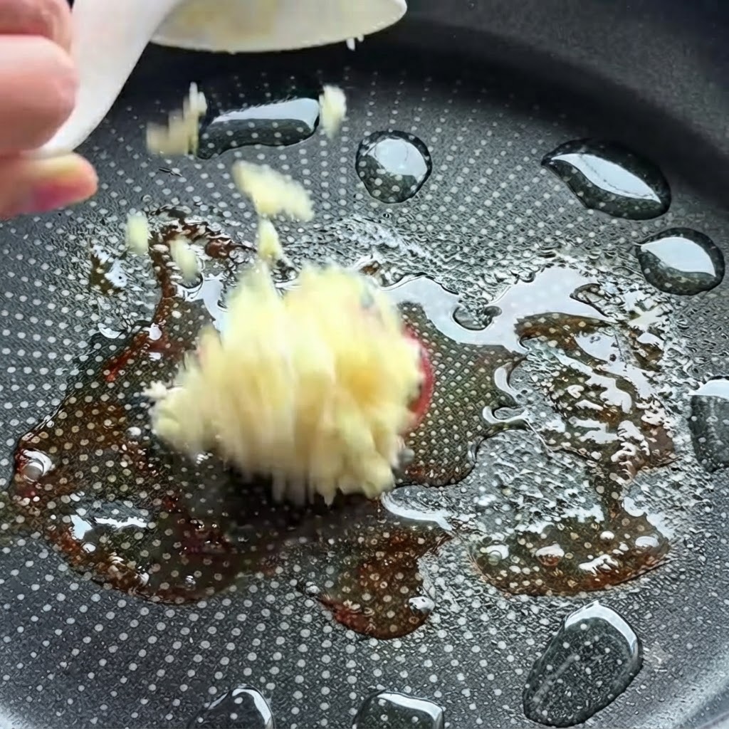 Ajo picado siendo arrojado a una sartén caliente con aceite.