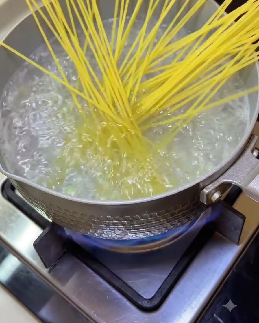 Fideos de espagueti cayendo en una olla con agua hirviendo burbujeante en la estufa.