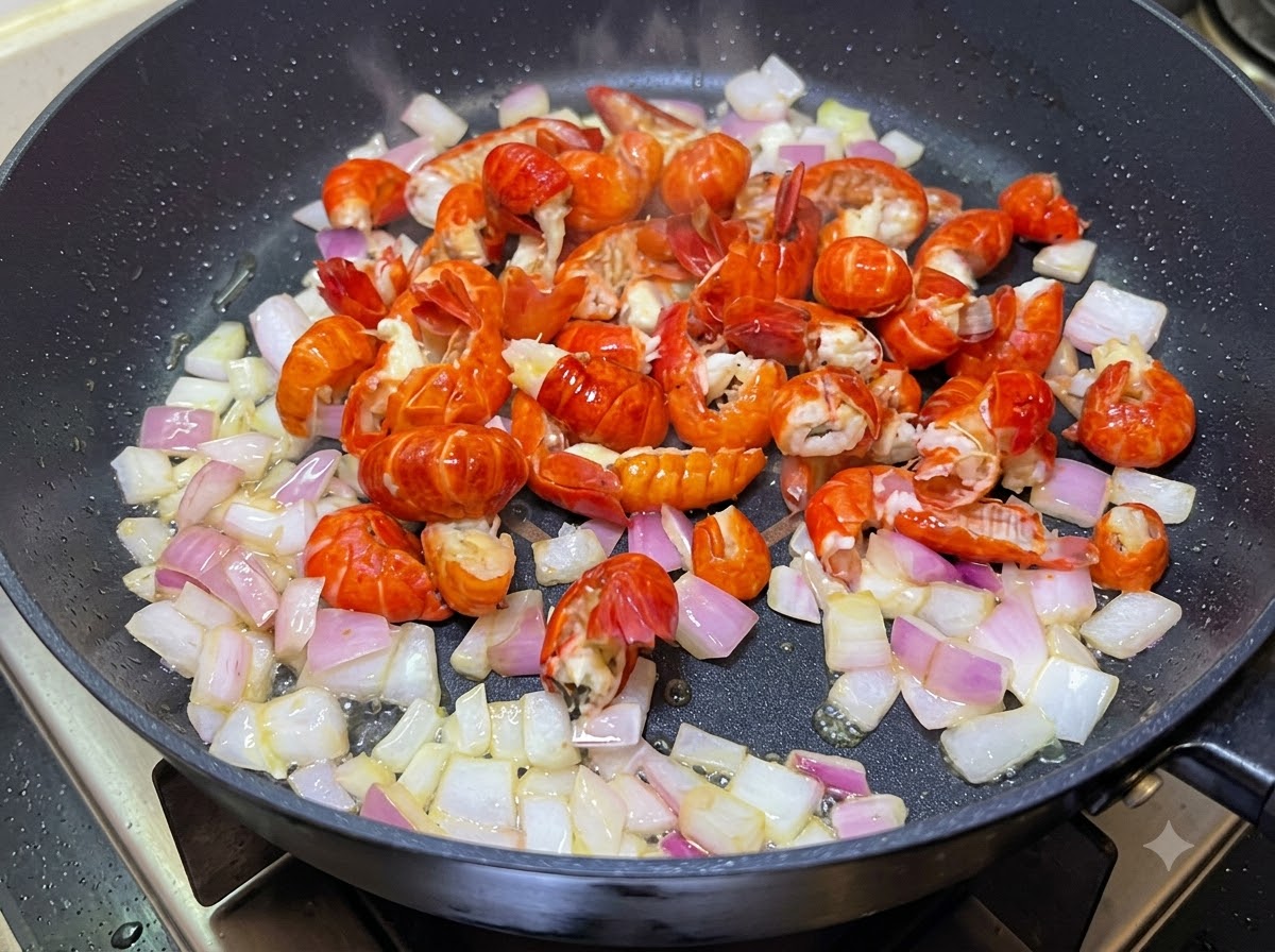 Colas de cangrejo de río y cebollas picadas cocinándose juntas en una sartén.