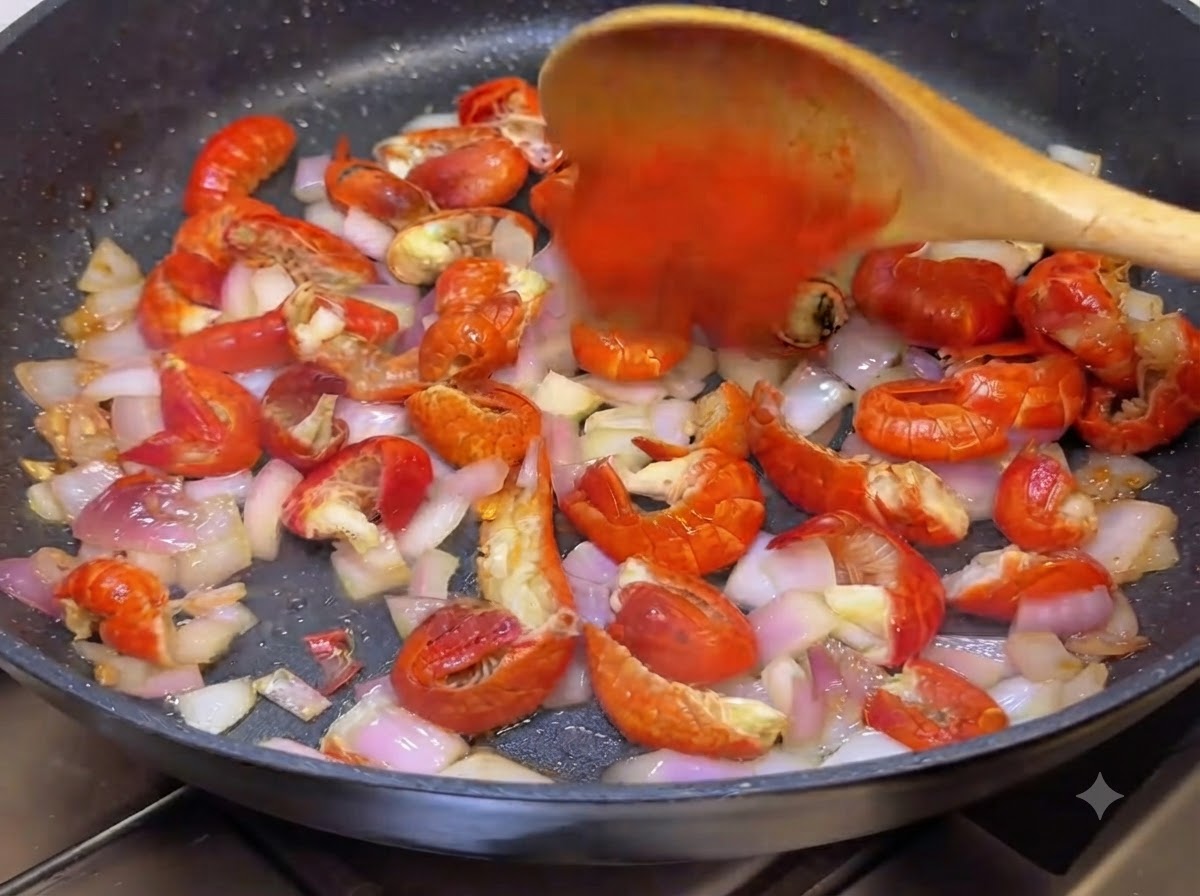 Chile en polvo y salsa picante coreana siendo revueltos en la sartén con una cuchara de madera.