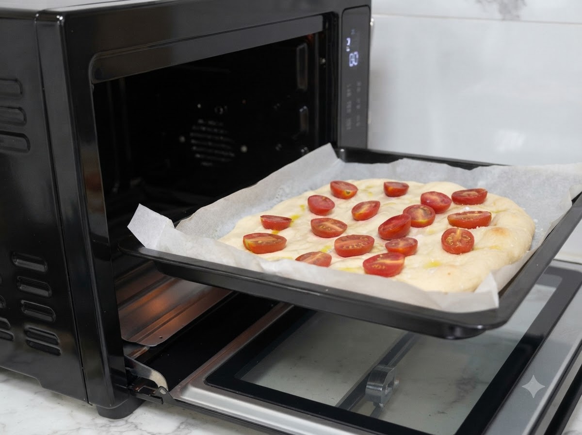 Una bandeja de horno con la masa de pizza preparada se introduce en un horno negro.