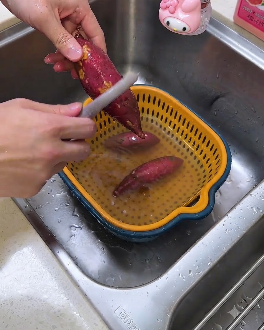 Una persona pelando batatas crudas sobre el fregadero de la cocina con un pelador de verduras.