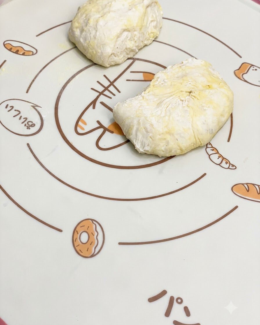 Trozos de masa de pizza fermentada reposando sobre un tapete de horneado de silicona con patrones.