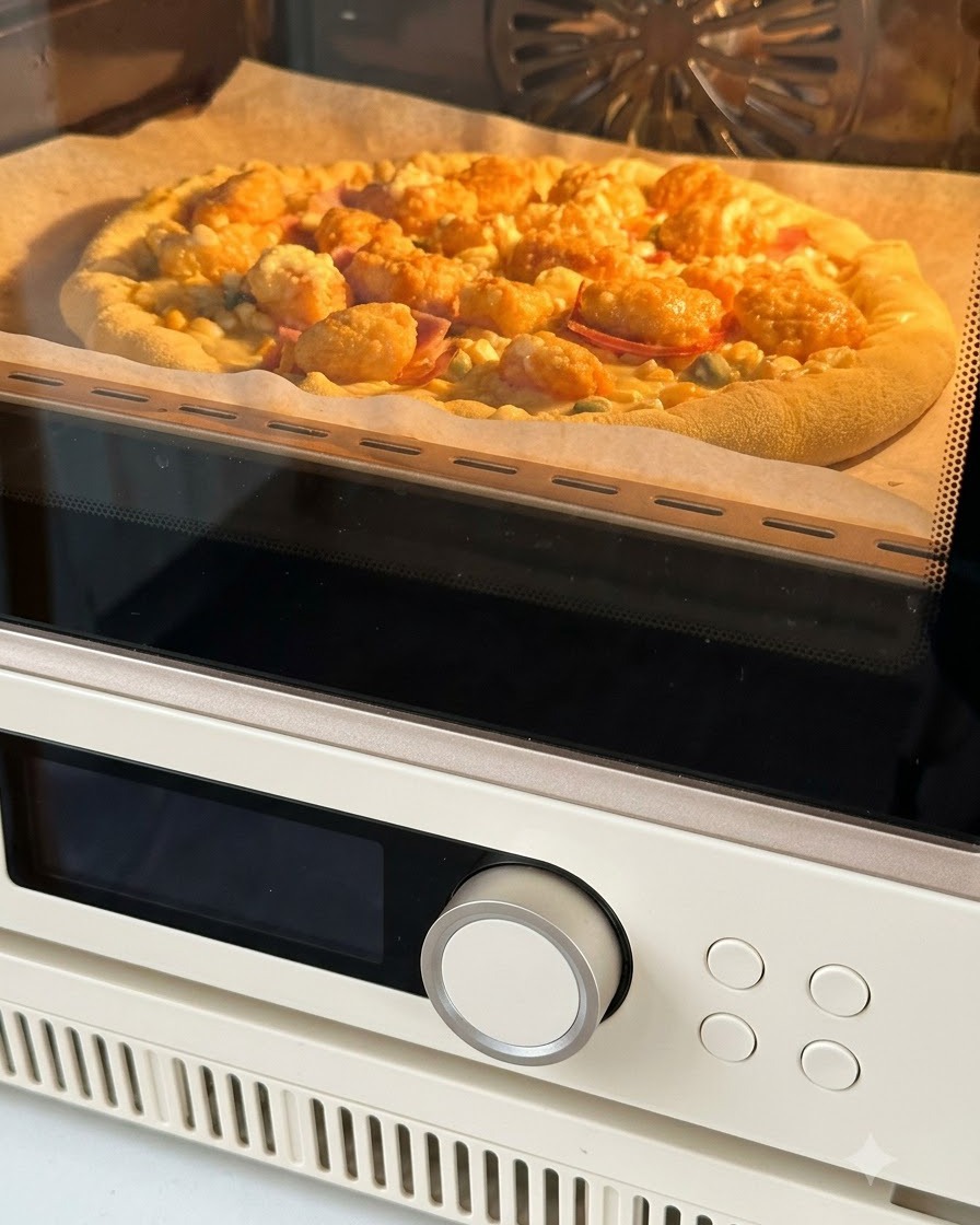 Pizza montada sobre papel pergamino siendo introducida en un horno para hornearse con el interior brillando de color naranja cálido.