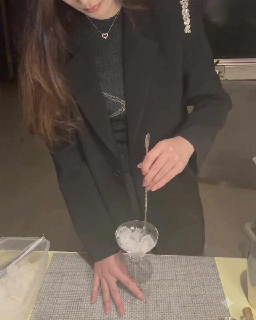 Cubitos de hielo dentro de una copa de martini siendo removidos con una cuchara de cóctel para enfriarla.