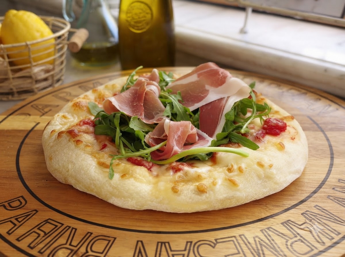Queso parmesano recién rallado cayendo sobre una pizza preparada cubierta con verduras y carne curada.