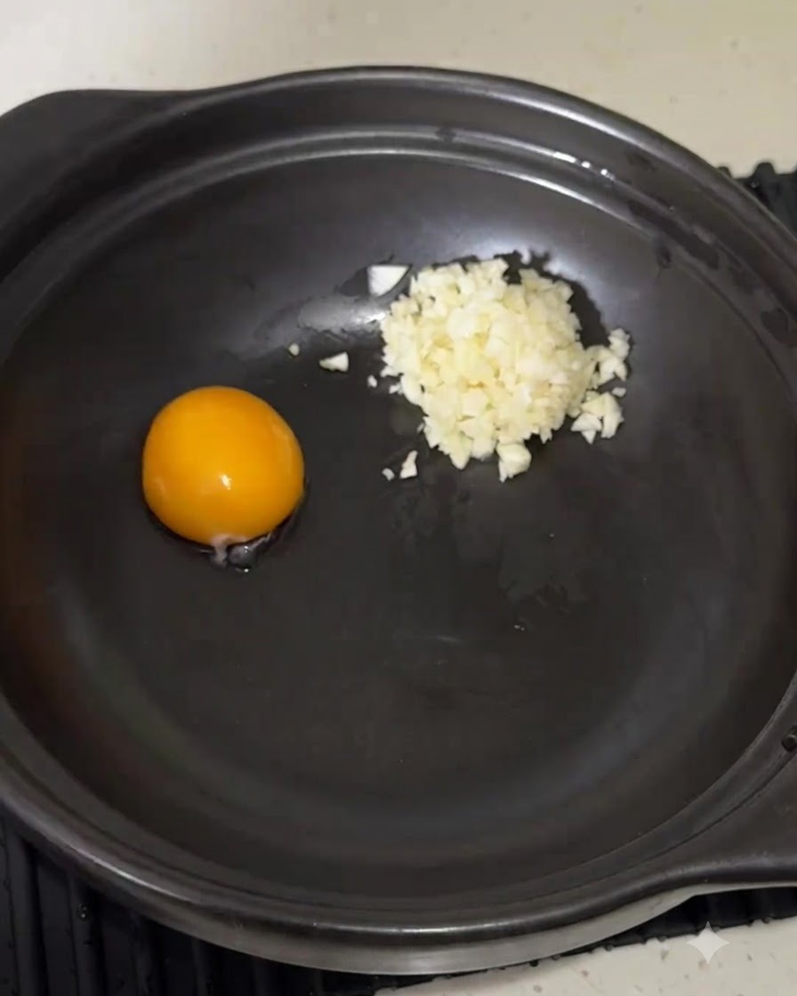 Polvo de condimento para fideos instantaneos vertido en la olla junto a la yema de huevo y el ajo.