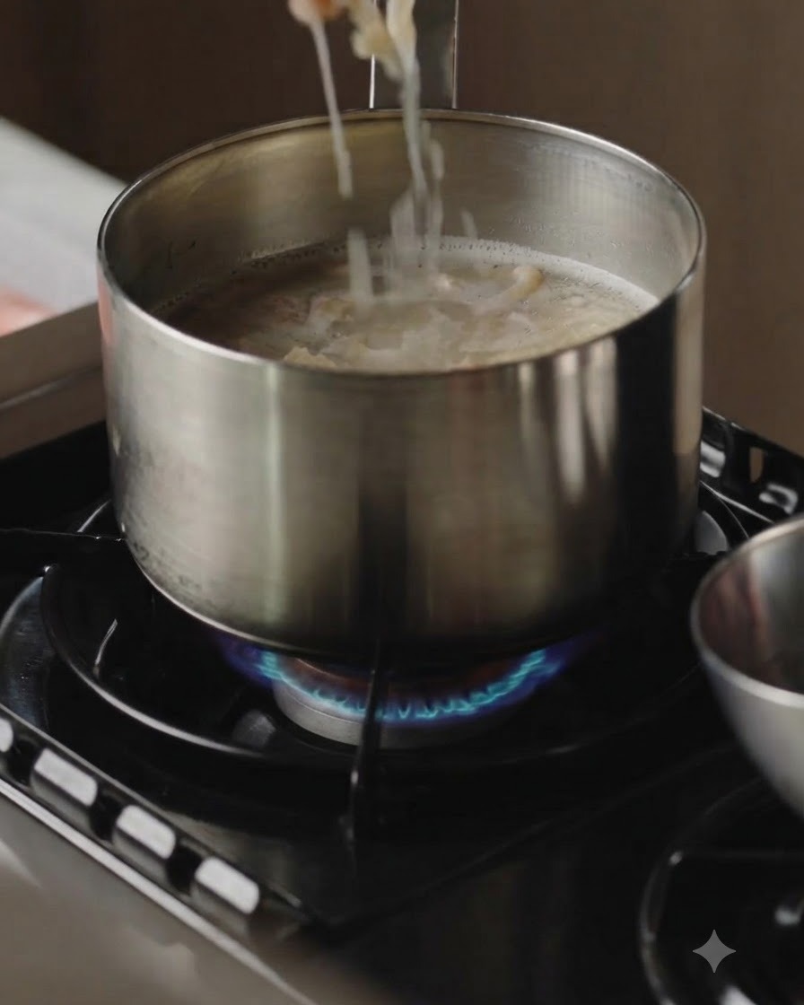 Rodajas de carne cocinadas siendo retiradas de una olla de caldo hirviendo con palillos.