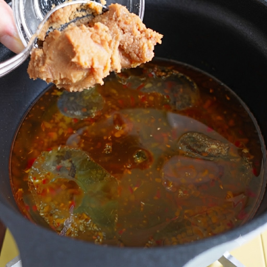 Pasta de miso agregada a una olla de caldo sazonado.