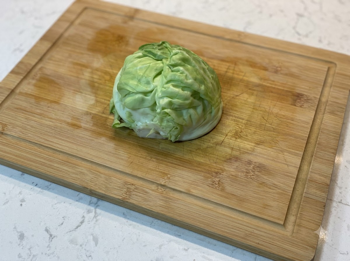 Un gajo de col verde fresca reposando sobre una tabla de cortar de madera.