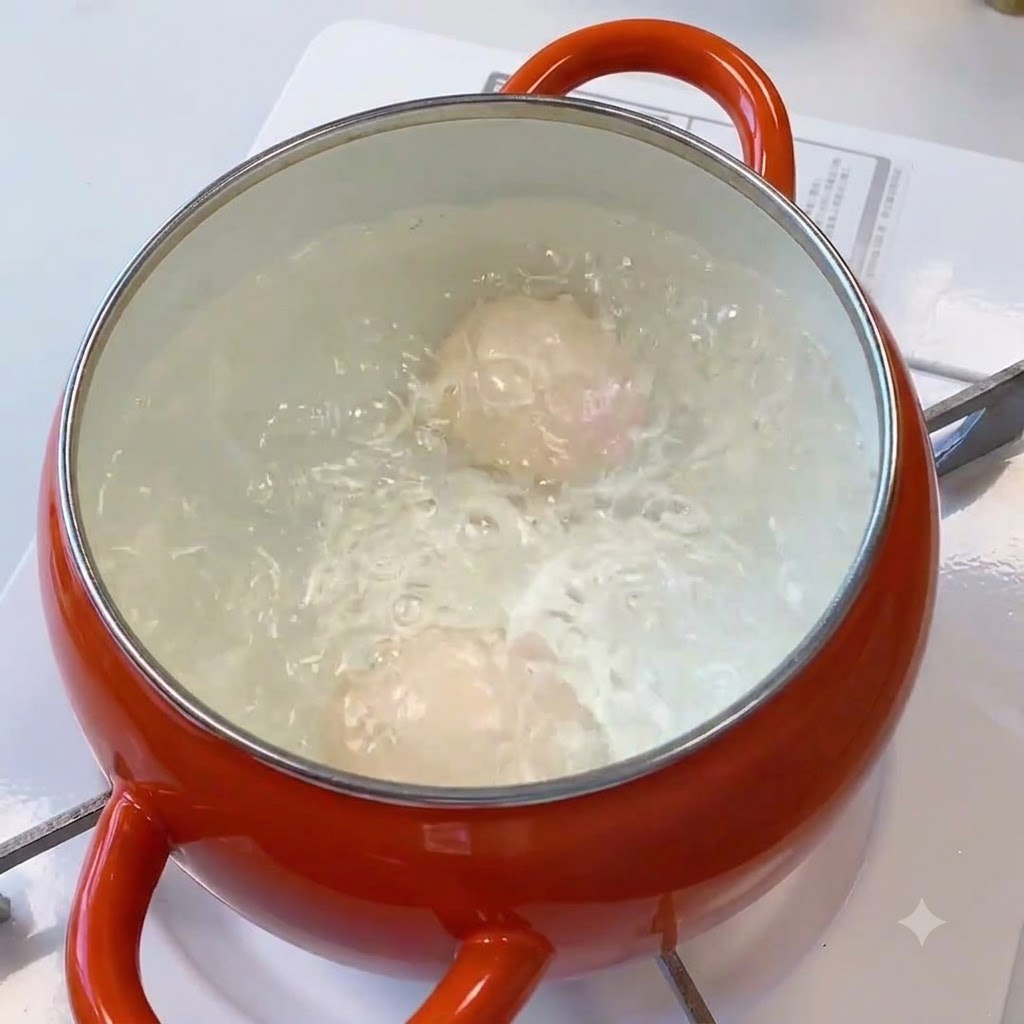 Huevos hirviendo vigorosamente dentro de una olla naranja con agua.