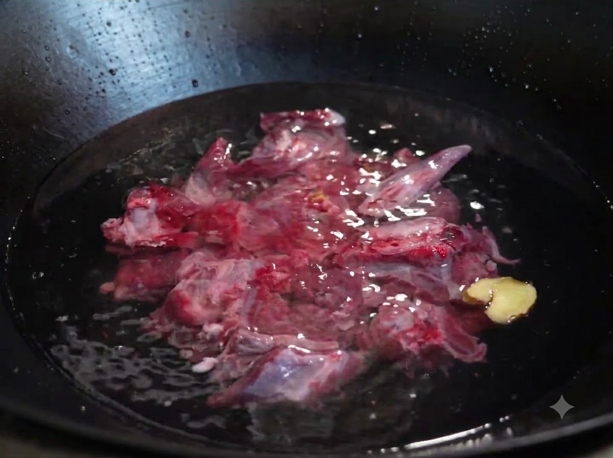 Costillas de res crudas sumergidas en agua fría dentro de un wok con rodajas de jengibre y una cebolla verde.