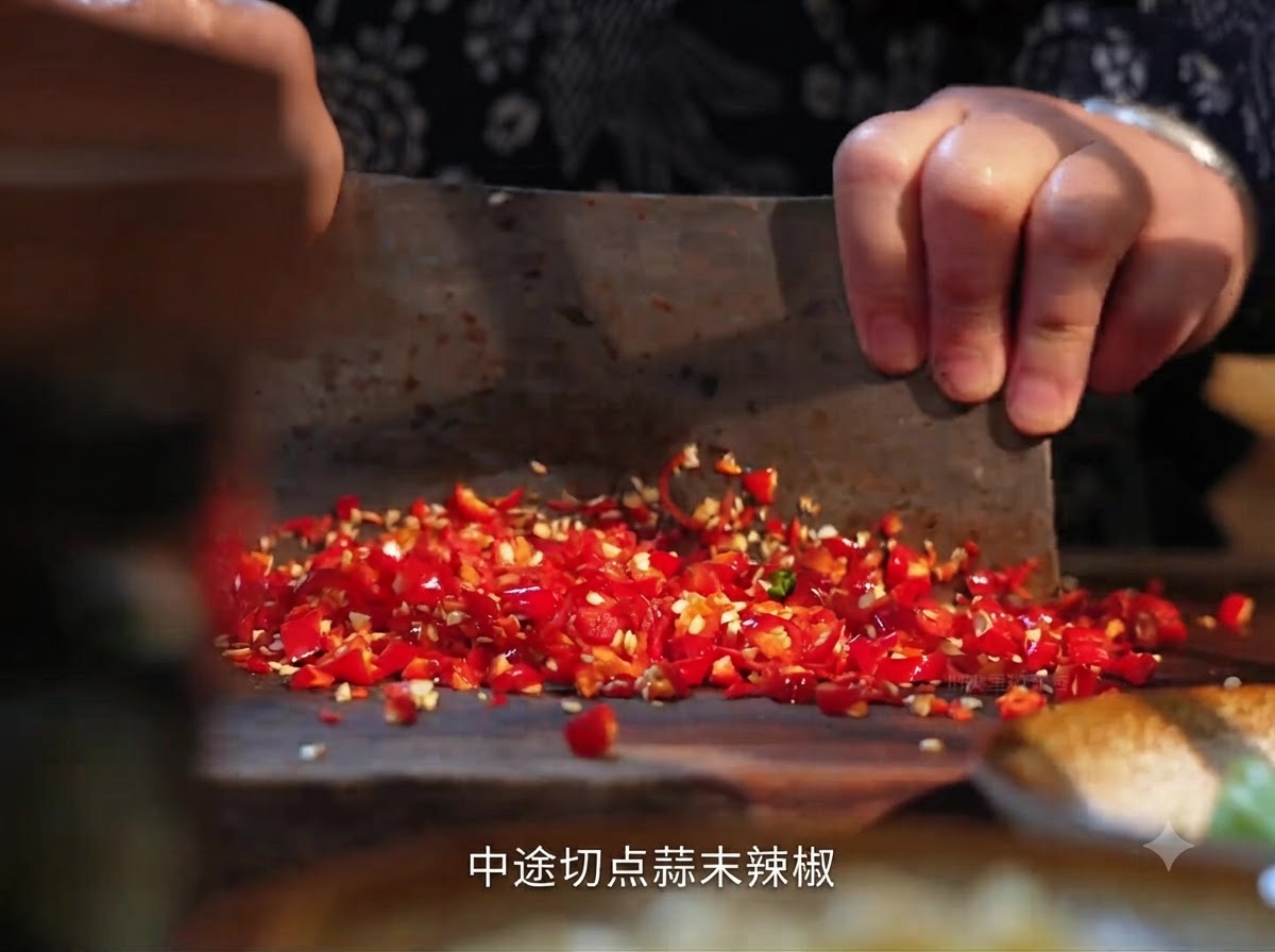 Chiles rojos frescos siendo picados en una tabla de madera con un cuchillo de carnicero.