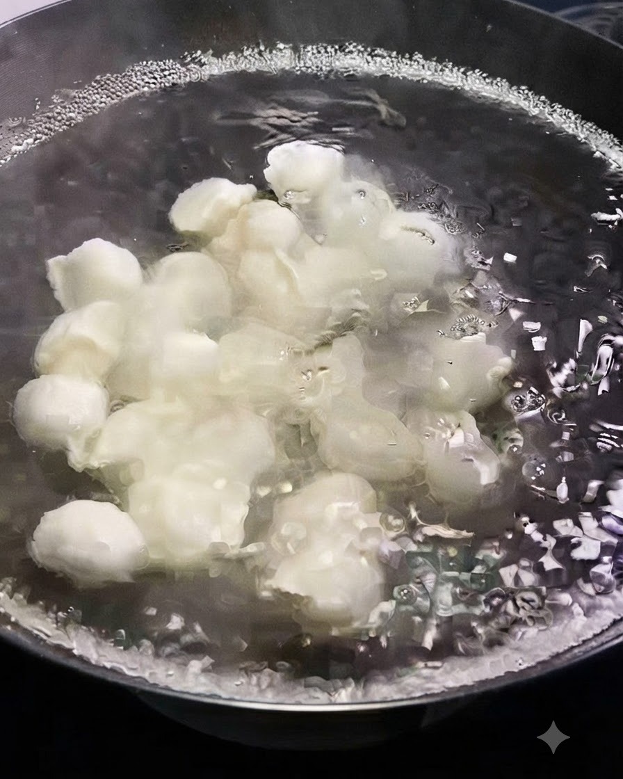 Una vista de cerca de dumplings blancos frescos cocinándose en una olla con agua hirviendo rápidamente.