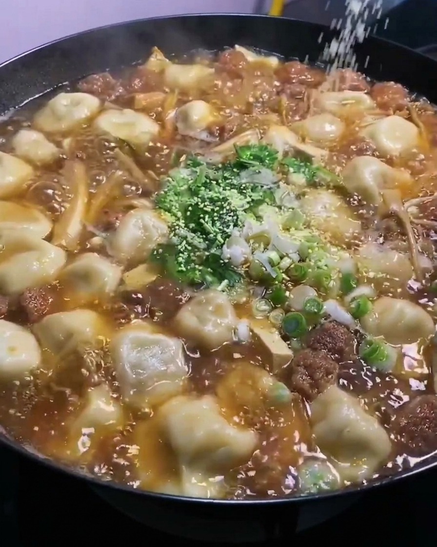 Polvo de caldo de pollo siendo esparcido desde arriba en el wok burbujeante.