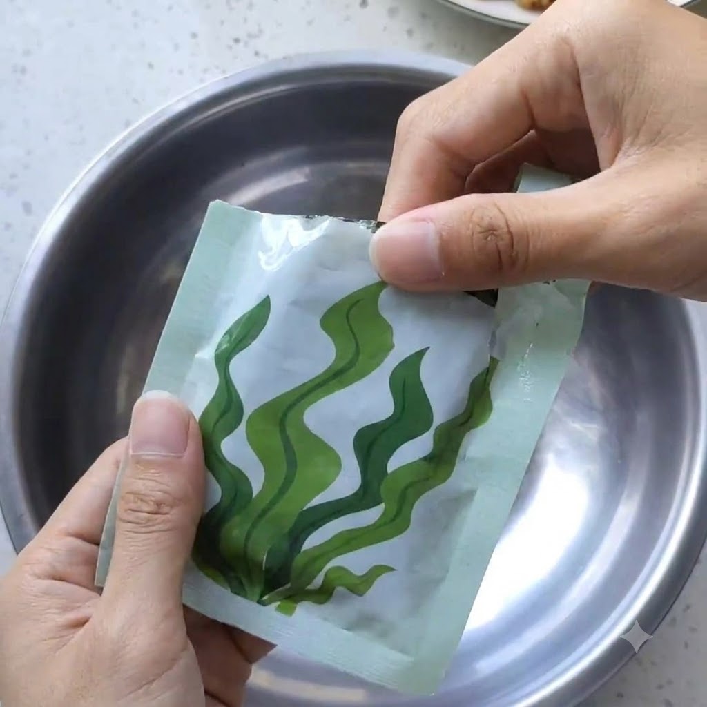Un par de manos abriendo un paquete de alga kombu comprimida sobre un bol de metal.