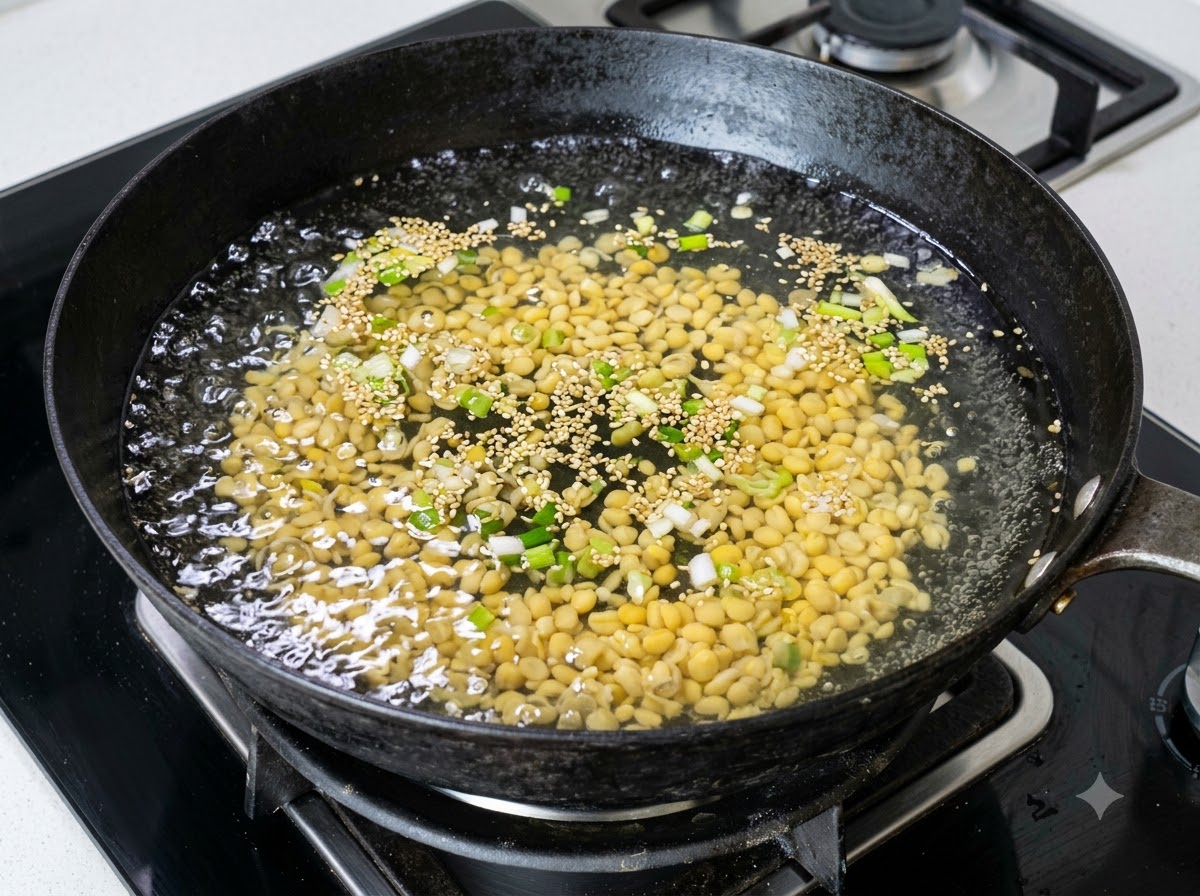 Una gran cantidad de brotes de soja amarillos hirviendo en un wok con agua y cebollinos picados.