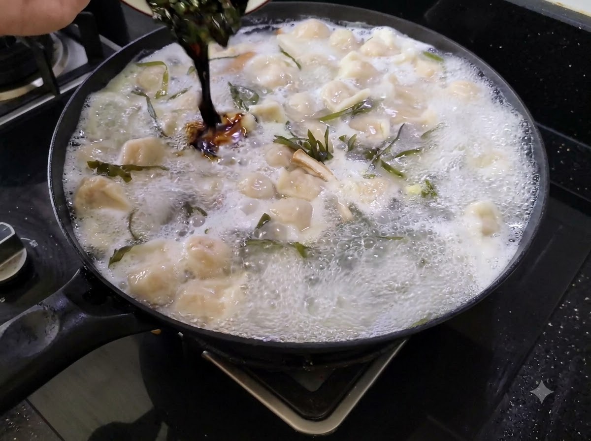 Salsa de condimento oscura siendo vertida desde un plato pequeño en una olla grande de sopa de dumplings hirviendo.
