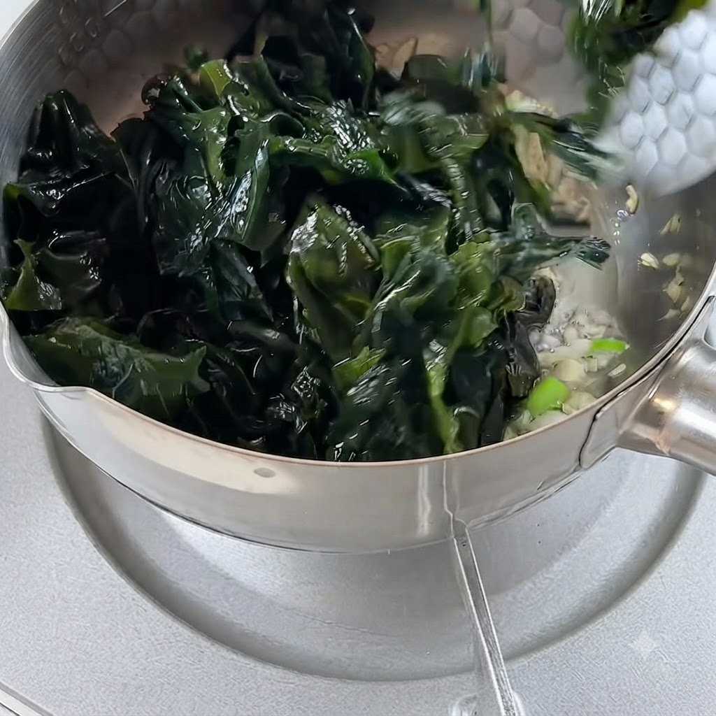 Algas rehidratadas incorporándose a la olla con el ajo y la cebolleta sofritos.