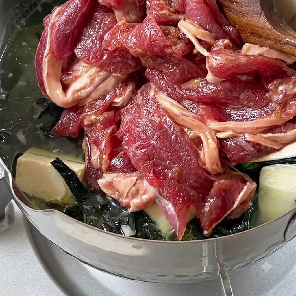 Tiras de ternera marinada echándose en una olla de sopa a fuego lento.