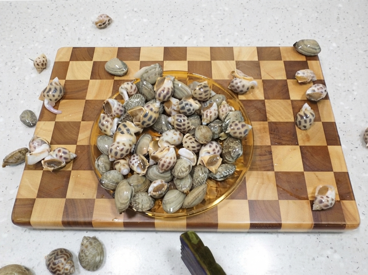 Un plato lleno de caracoles de mar manchados crudos reposando en una tabla de cortar de madera.