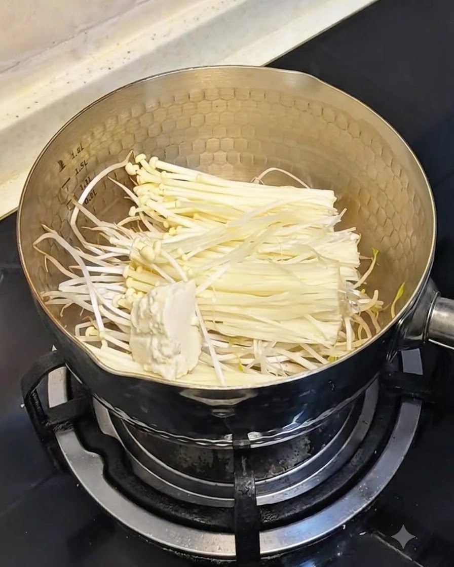 Una cuchara agregando tofu sedoso suave dentro de la olla que contiene brotes de soja y setas.