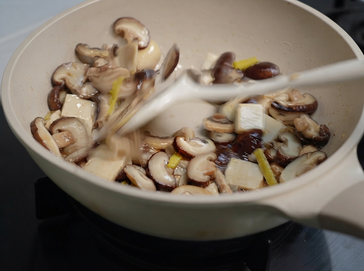 Hongos mixtos y jengibre siendo salteados en una sartén con una espátula.