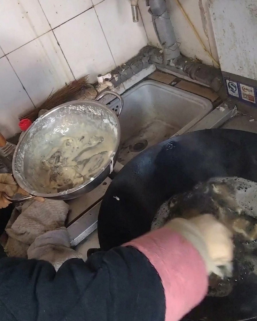 Frriendo tiras de champiñón rebozadas en un wok lleno de aceite caliente.