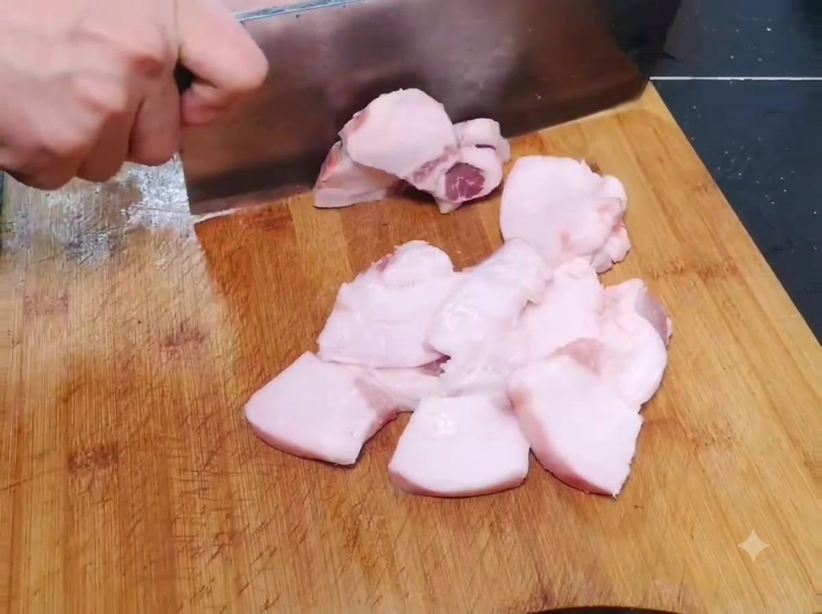 Trozos delgados y anchos de cerdo crudo cortándose en una tabla de cortar de madera.