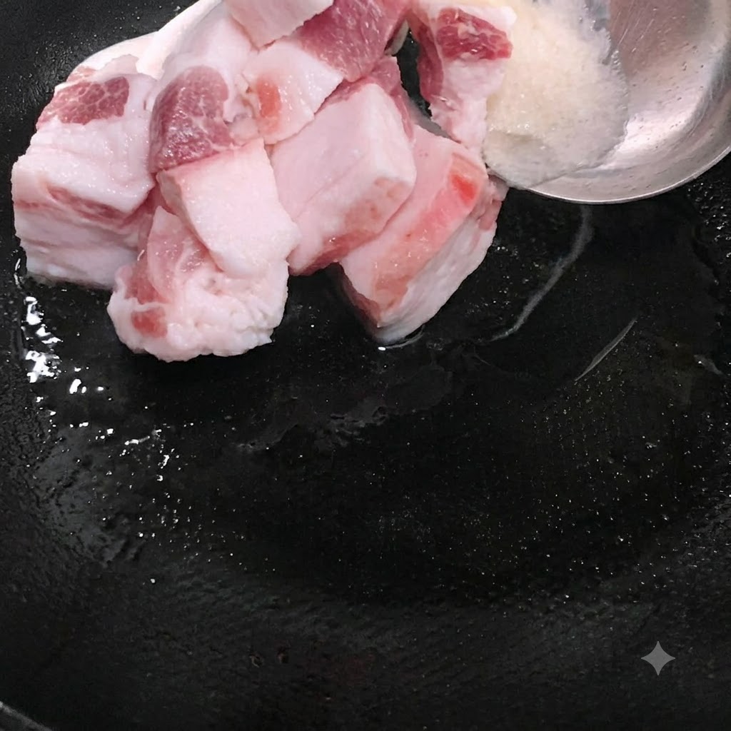 Rodajas de cerdo graso siendo colocadas en el wok junto con la manteca derretida.