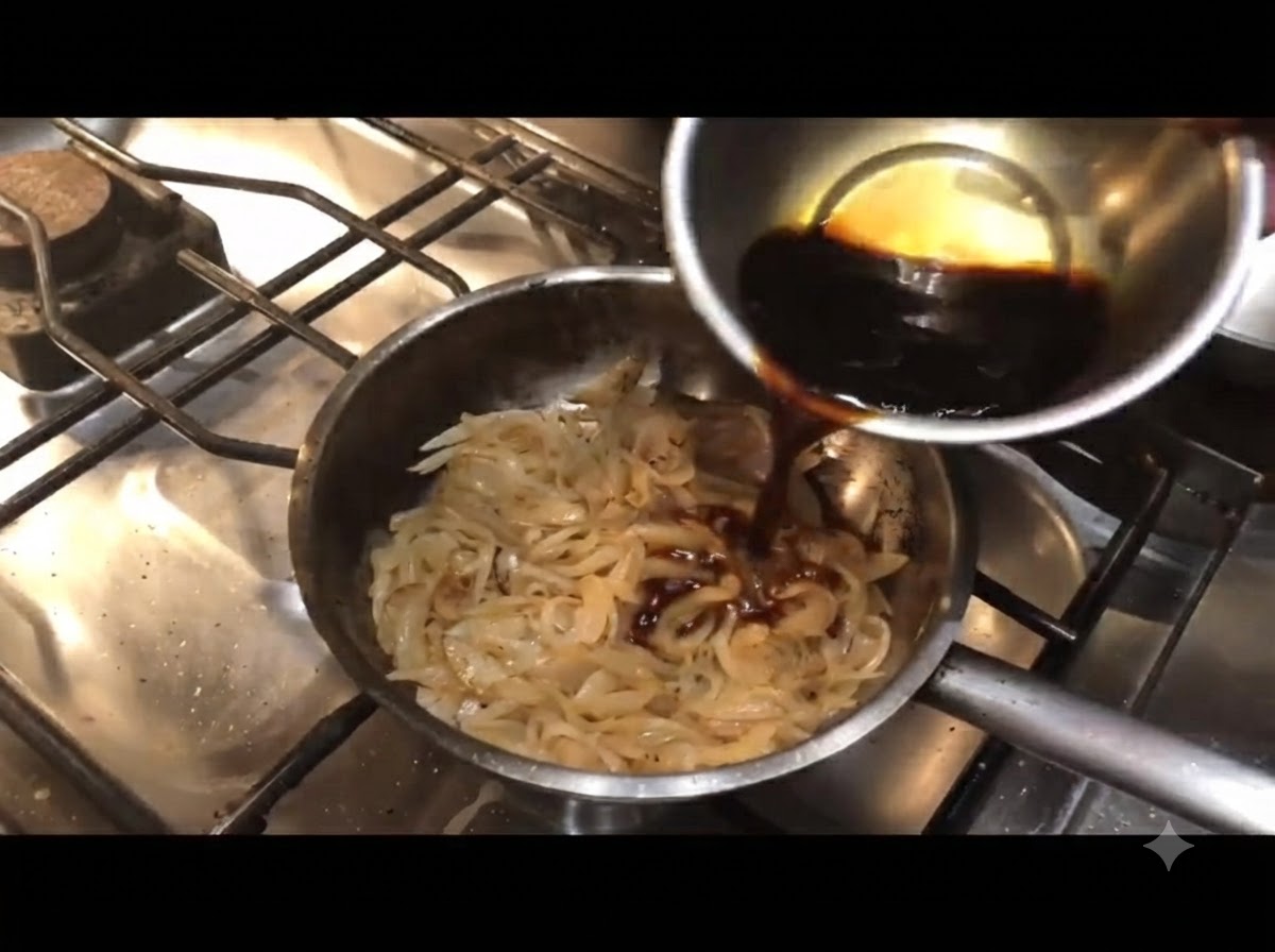 Salsa oscura siendo vertida desde un tazón pequeño en una sartén con cebollas cocinadas.