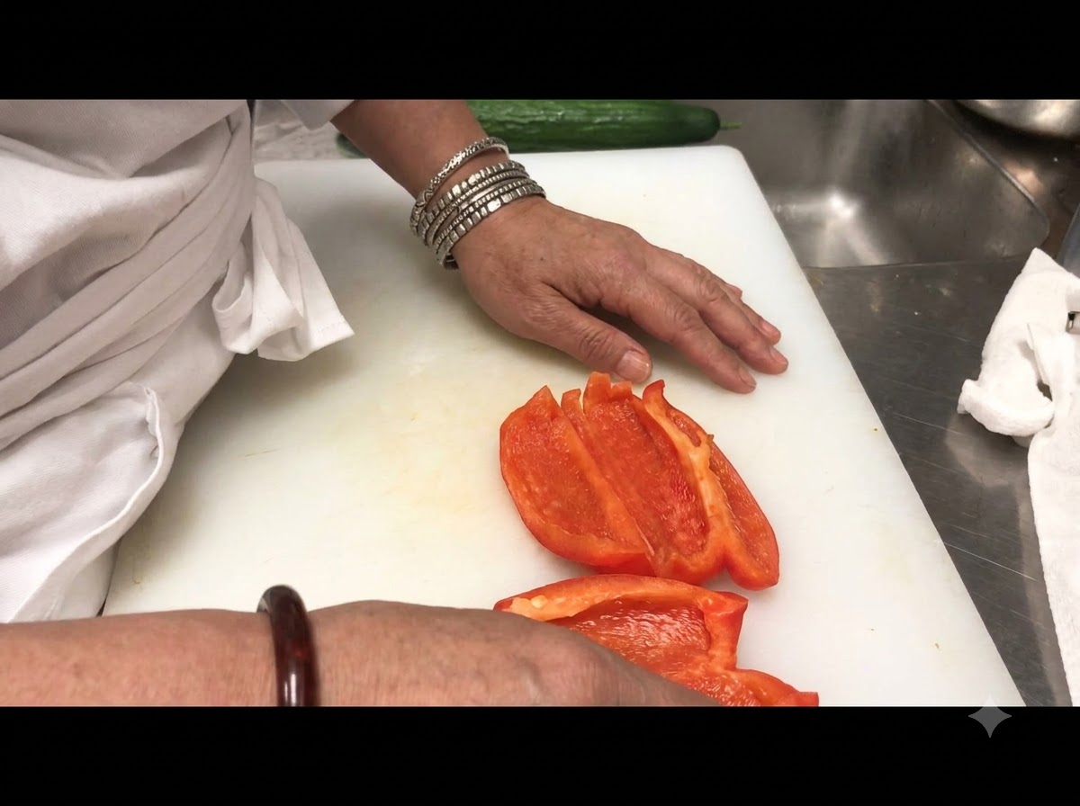 Tiras de pimiento rojo cortadas y dispuestas sobre una tabla de cortar blanca.
