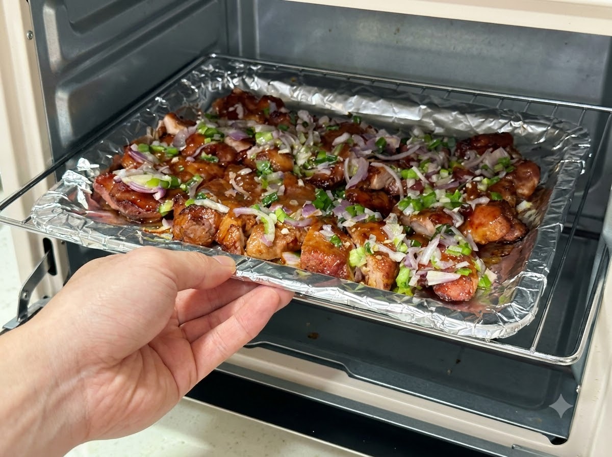 Una bandeja de horno cargada con rodajas de cerdo cubiertas de salsa siendo deslizada de vuelta a una freidora de aire.